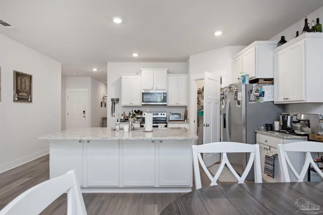 a kitchen with stainless steel appliances granite countertop a white cabinets and wooden floor