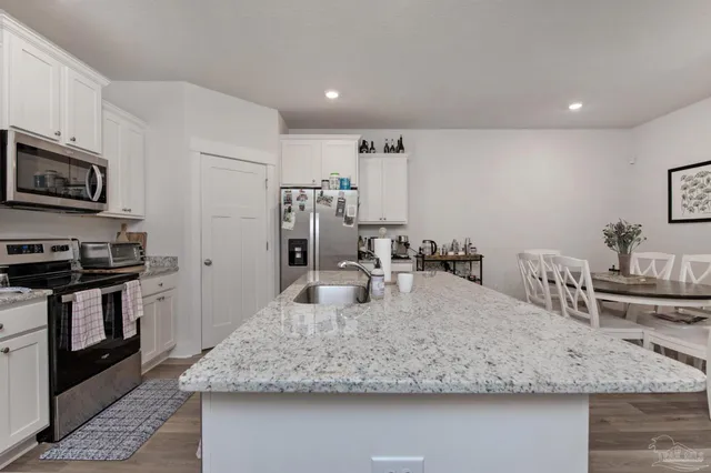 a kitchen with kitchen island granite countertop a sink and stainless steel appliances
