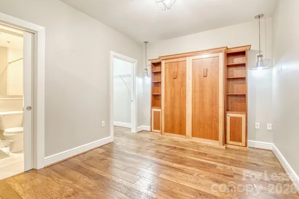 a view of an empty room with wooden floor and a bathroom