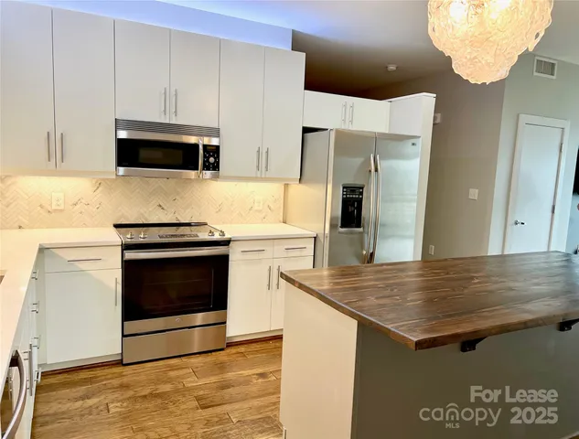 a kitchen with stainless steel appliances a stove microwave and sink