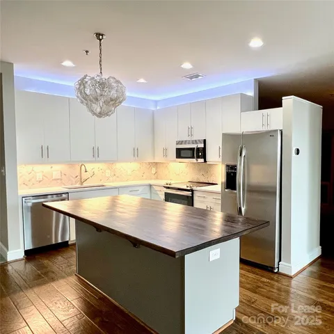 a kitchen with stainless steel appliances granite countertop a sink a refrigerator and a stove top oven