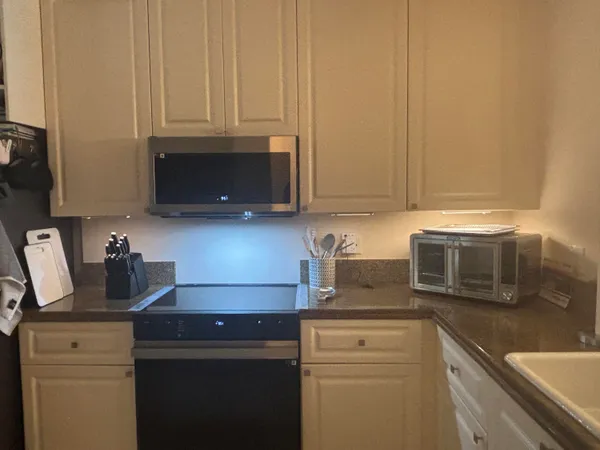 a kitchen with stainless steel appliances granite countertop white cabinets and a stove top oven