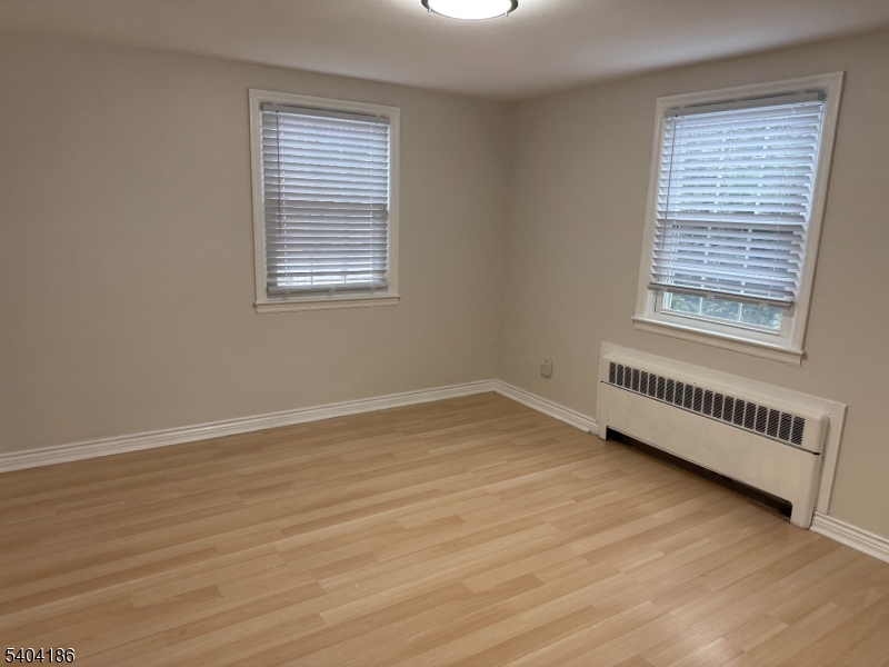 445 Morris Avenue, Unit 1A Springfield, NJ 07081 - Photo 8 of 9 a view of an empty room with wooden floor and a window