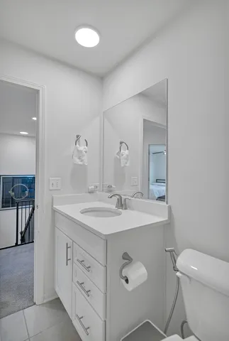 a spacious bathroom with a granite countertop sink a toilet and a mirror