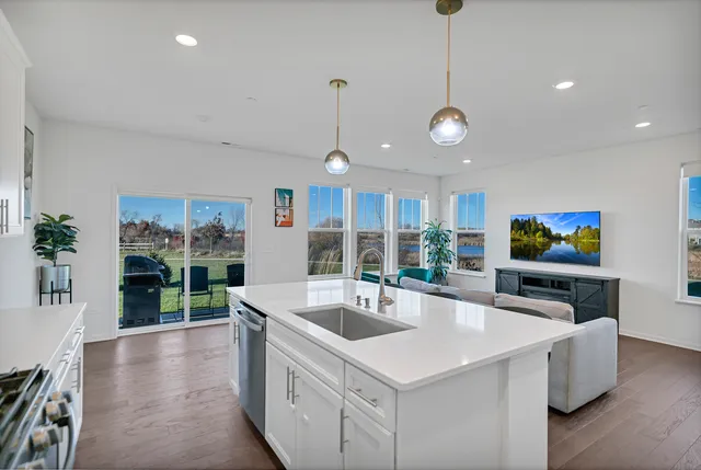 a large kitchen with stainless steel appliances a large center island attached withe living room