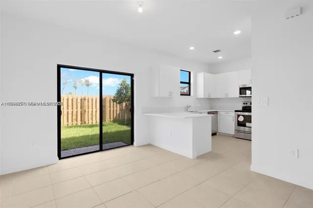 a view of kitchen with stainless steel appliances wooden floor and white cabinets