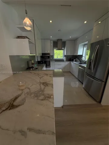 a large kitchen with a chandelier stainless steel appliances and living room