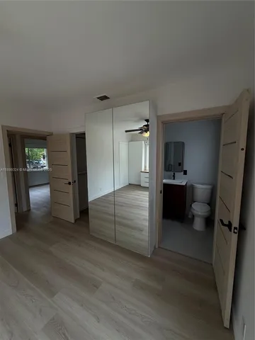 an empty room with wooden floor chandelier and windows