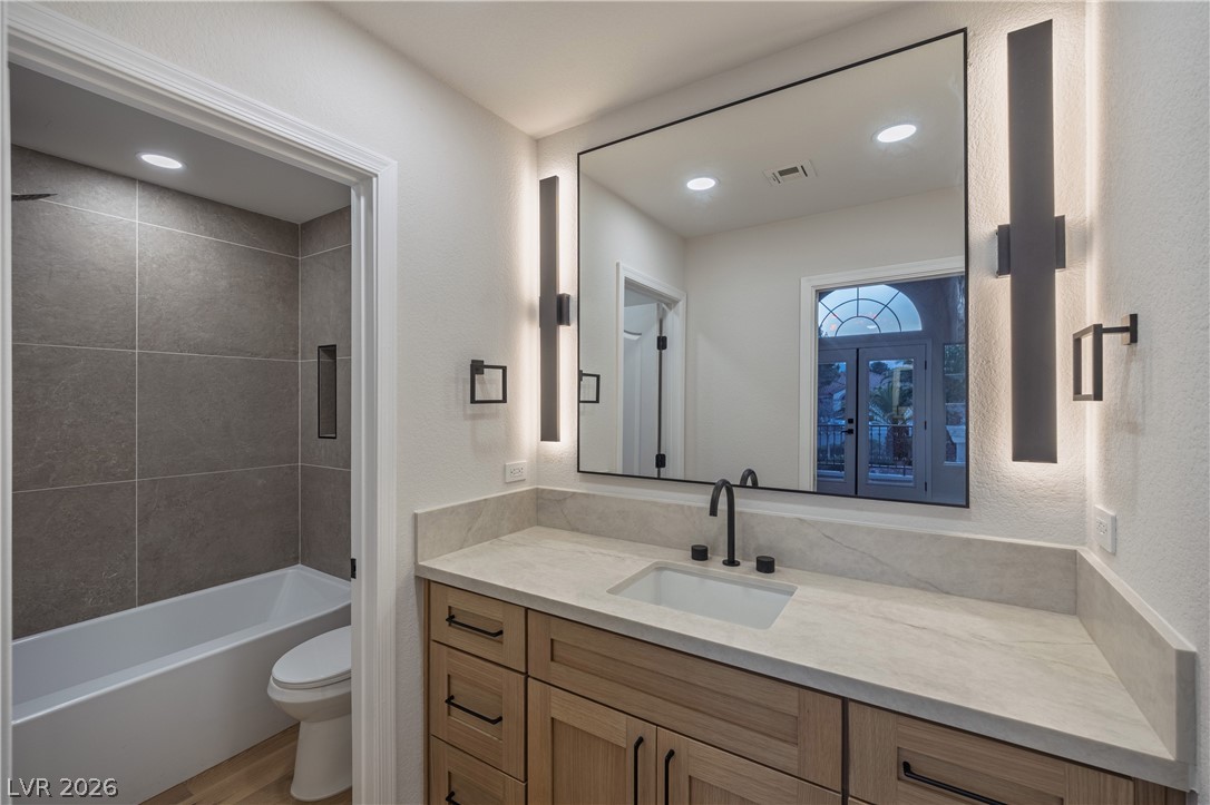 8800 Lusso Las Vegas, NV 89134 - Photo 68 of 85 Full bath with vanity, a textured wall, washtub / shower combination, recessed lighting, and light wood-type flooring