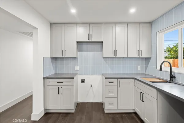 a kitchen with white cabinets and sink