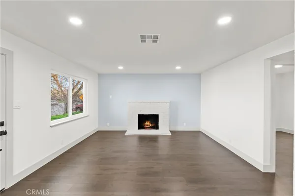 an empty room with windows and fireplace