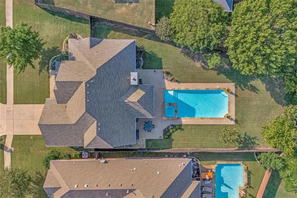 an aerial view of a house with swimming pool and large trees