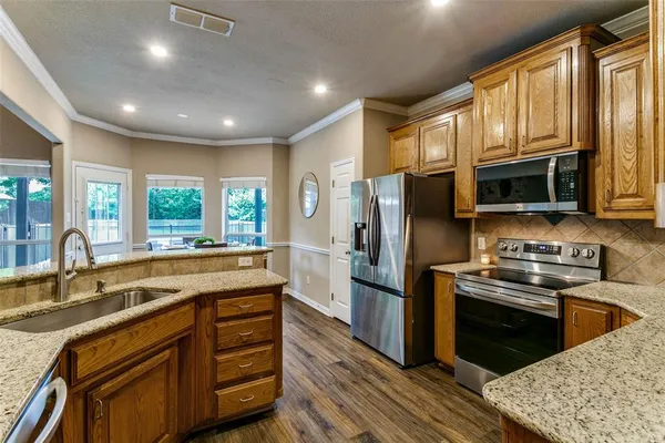 a kitchen with stainless steel appliances granite countertop a sink stove microwave and refrigerator