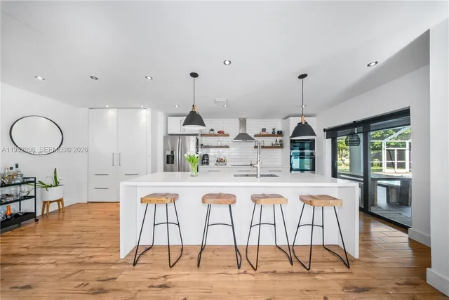 a kitchen with stainless steel appliances kitchen island granite countertop a table chairs in it and wooden floors