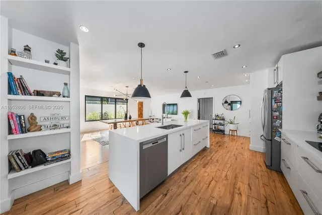 a large kitchen with stainless steel appliances a stove a sink dishwasher and a refrigerator with wooden floor