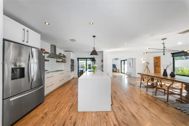 a living room with stainless steel appliances furniture a refrigerator and a kitchen view