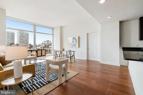 a large white kitchen with kitchen island a sink wooden floor and a refrigerator