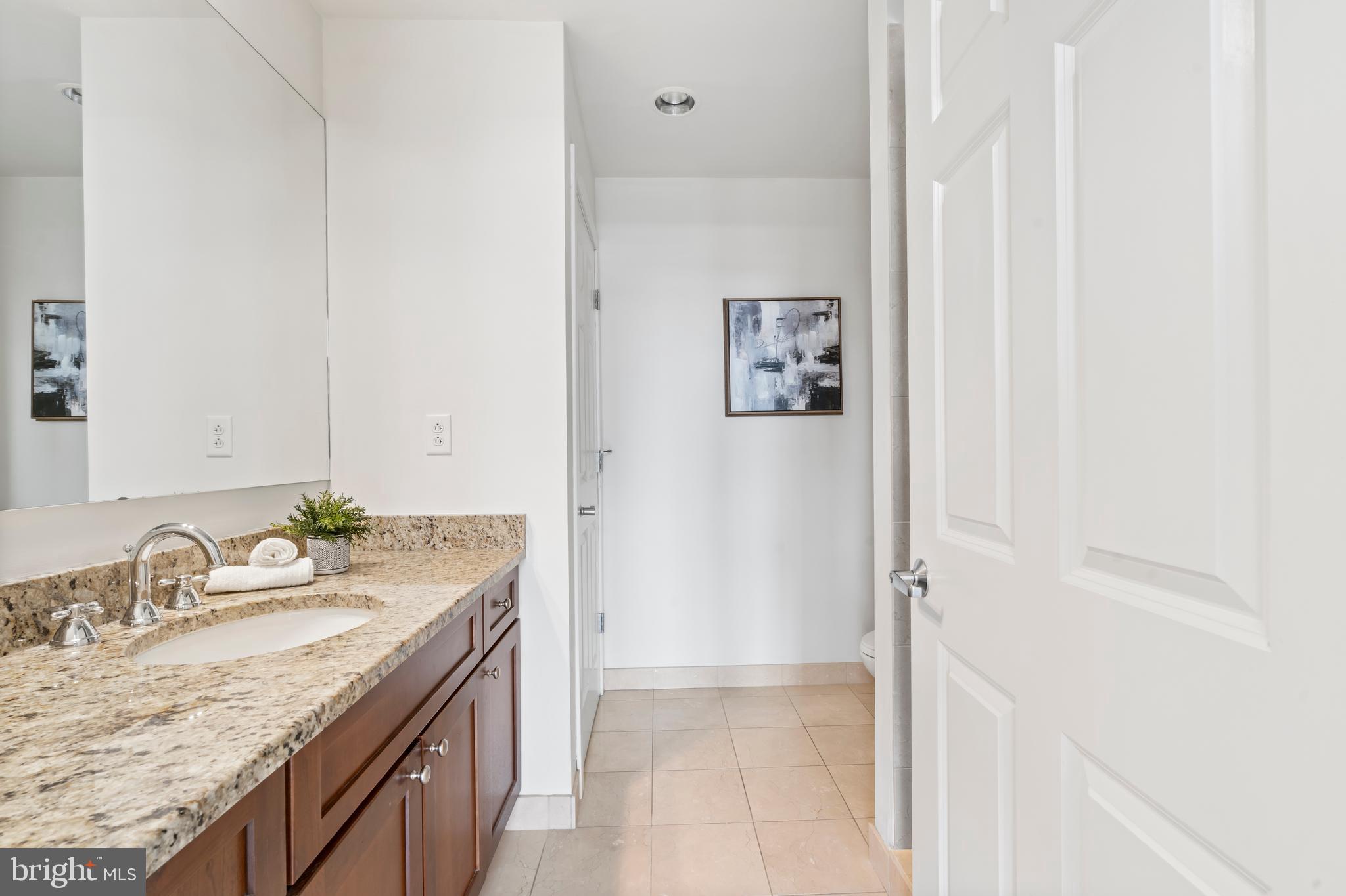 22 South Front Street, Unit 603 Philadelphia, PA 19106 - Photo 40 of 44 a bathroom with a granite countertop sink a mirror and a shower