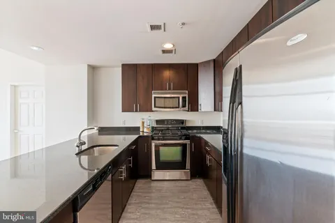 a kitchen with granite countertop a stove a sink and a microwave