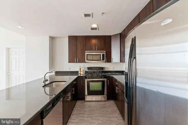 a kitchen with granite countertop a stove a sink and a microwave