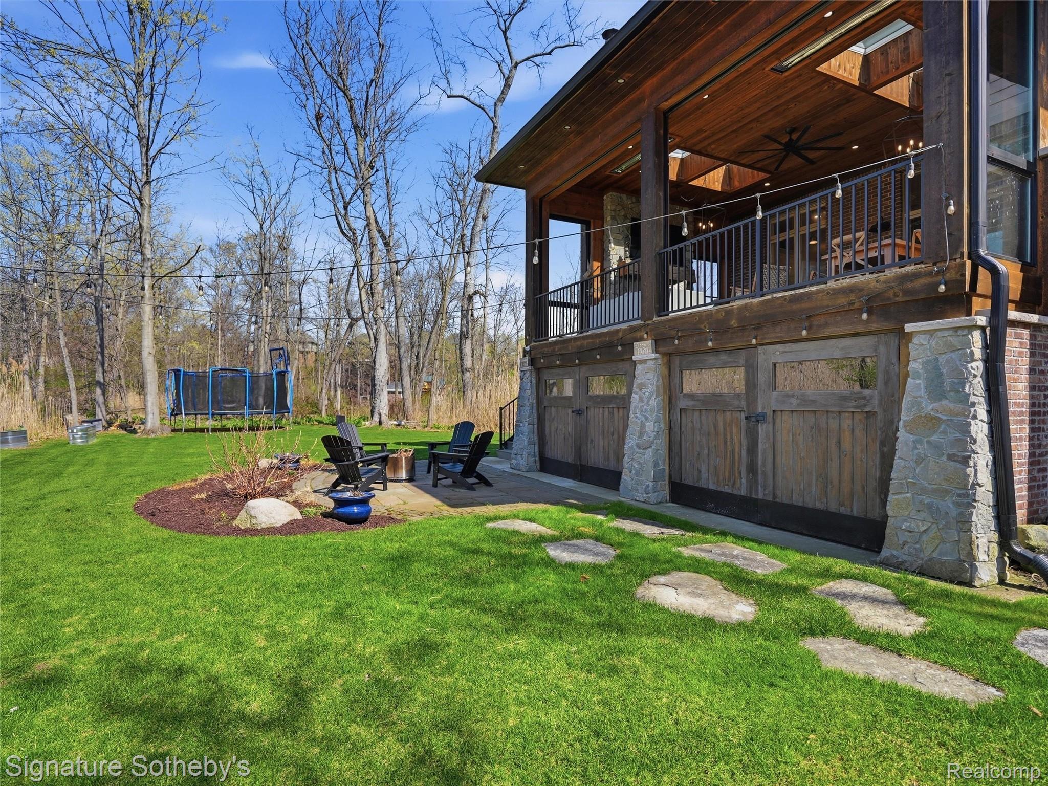 1595 Carriage Way Rochester, MI 48307 - Photo 19 of 78 View of grassy yard featuring a balcony, a ceiling fan, an outdoor fire pit, a trampoline, and a patio area