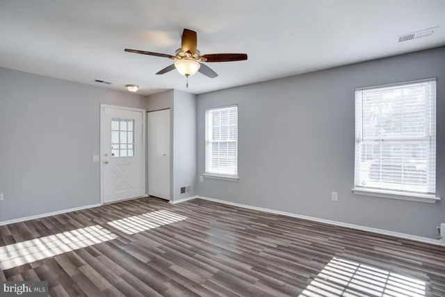 a view of an empty room with wooden floor and a window