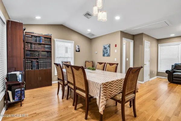 a kitchen with stainless steel appliances granite countertop a refrigerator a stove top oven a sink dishwasher and white cabinets with wooden floor