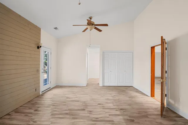 a view of empty room with wooden floor and ceiling fan