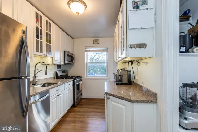 a kitchen with stainless steel appliances granite countertop a refrigerator a stove and a sink with wooden floor