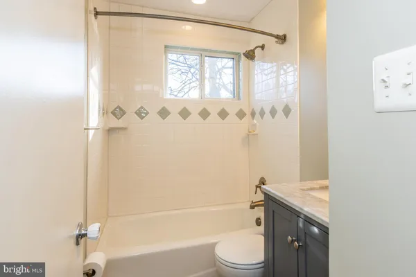 a bathroom with a granite countertop bathtub shower sink vanity and toilet