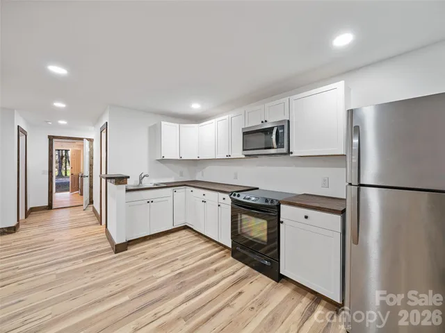 a kitchen with a refrigerator a stove top oven and white cabinets