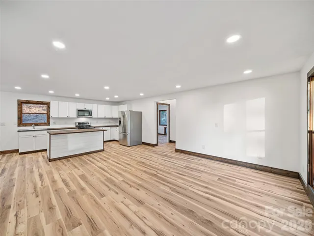a view of kitchen with kitchen island a sink wooden floor and black appliances