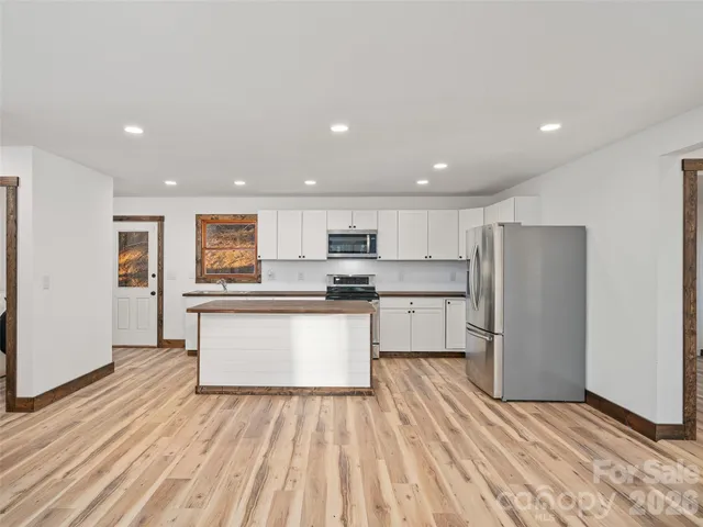 a kitchen with stainless steel appliances granite countertop a refrigerator sink and white cabinets