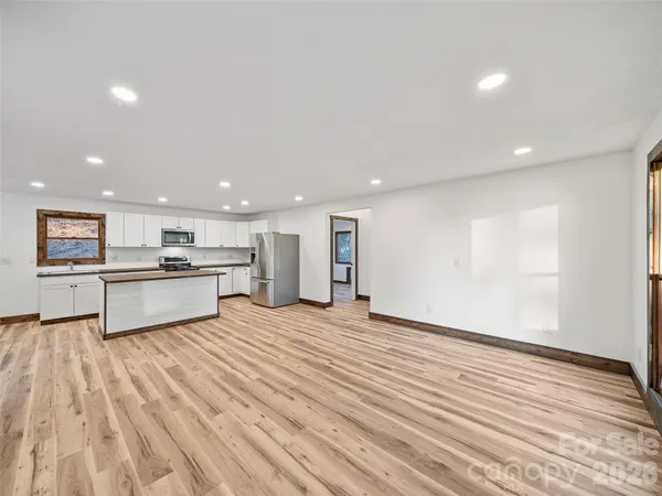 a view of kitchen with kitchen island a sink wooden floor and black appliances