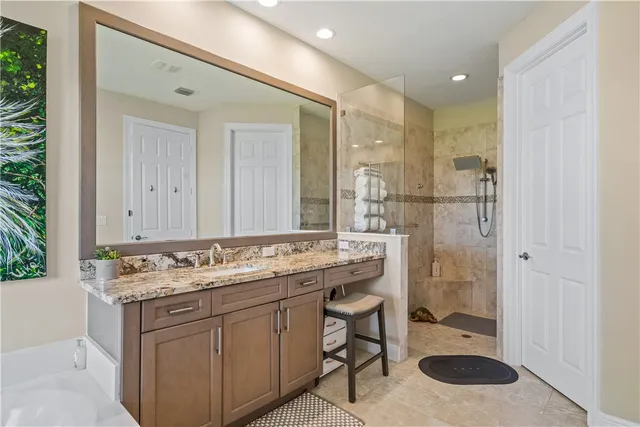 a bathroom with a granite countertop sink a toilet a mirror and shower