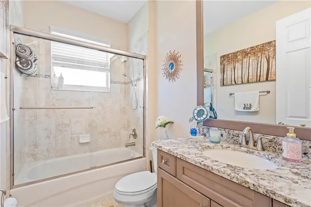 a bathroom with a granite countertop sink a toilet and shower