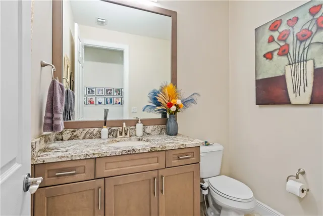 a bathroom with a granite countertop toilet sink and mirror