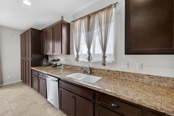 a kitchen with stainless steel appliances granite countertop a table chairs sink and refrigerator