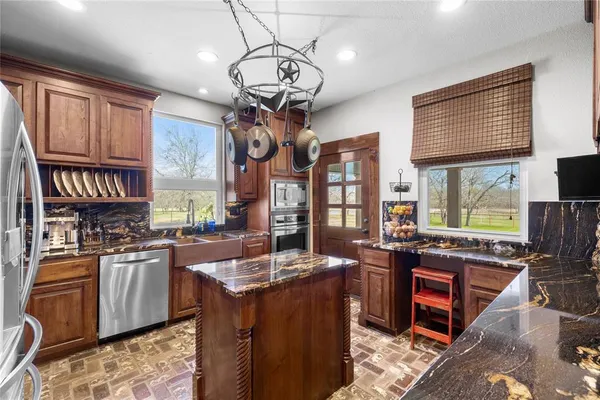 a kitchen with stainless steel appliances granite countertop a stove top oven a sink dishwasher a dining table and chairs with wooden floor