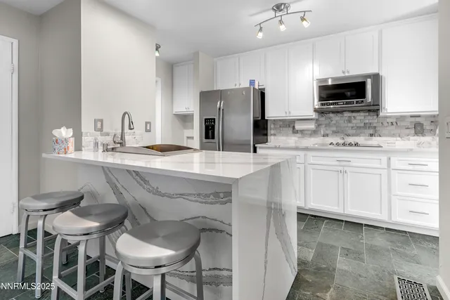 a kitchen with stainless steel appliances a sink and chairs