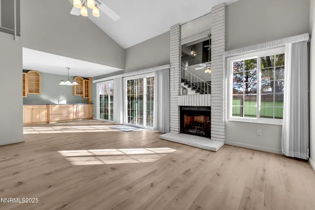 a view of an empty room with wooden floor fireplace and a window