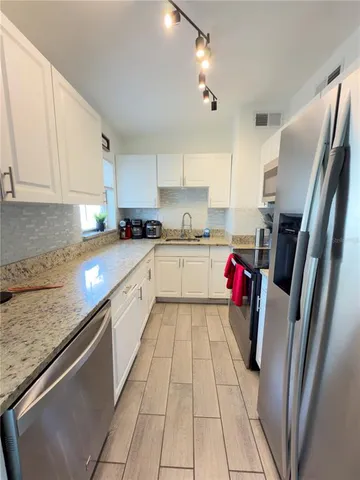 a large kitchen with stainless steel appliances granite countertop a sink dishwasher stove refrigerator and cabinets