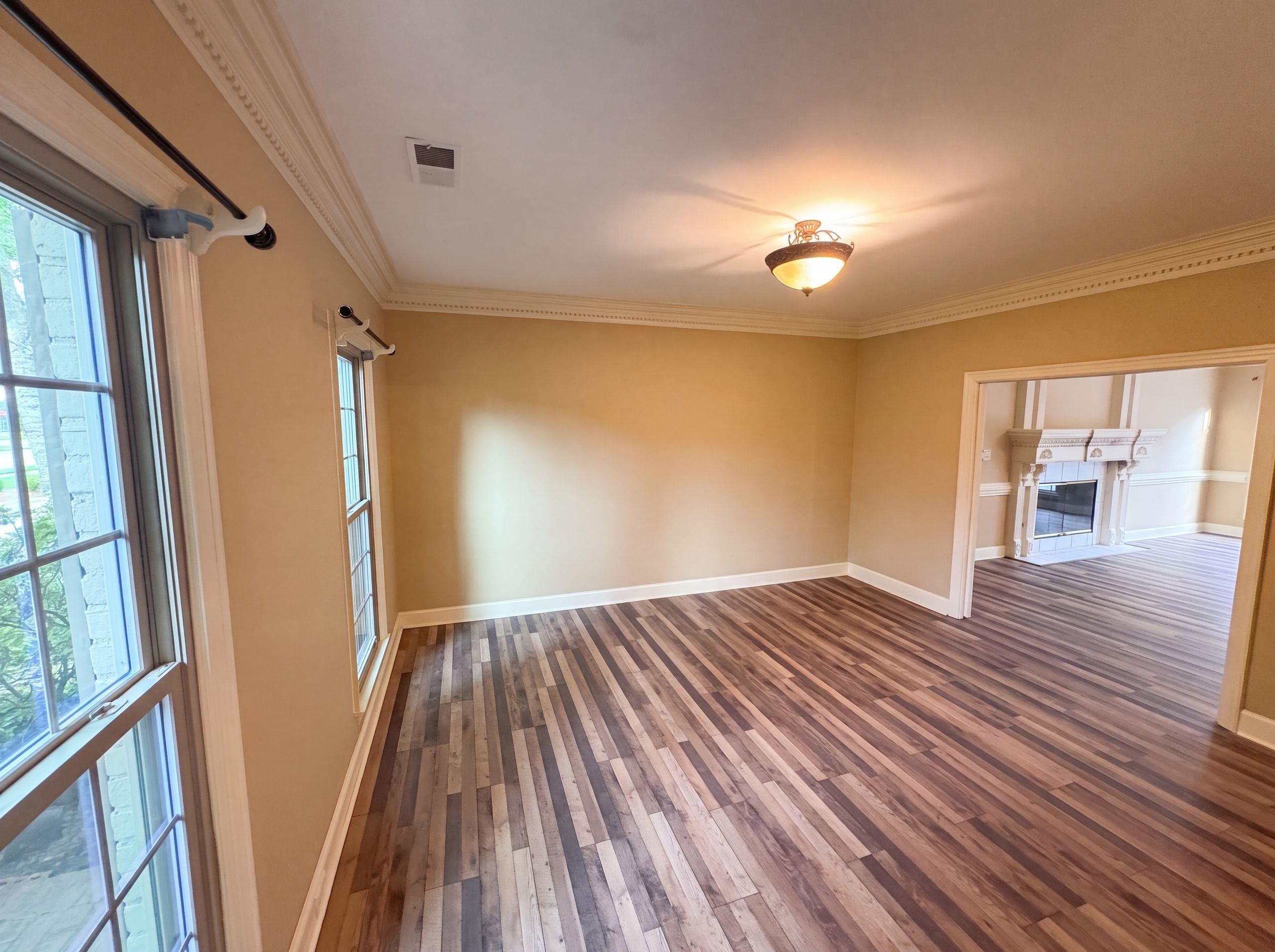 9424 Gotten Road Germantown, TN 38139 - Photo 9 of 27 Spacious room featuring multi-toned wood-finish flooring, two large windows, crown molding, and a semi-flush mount ceiling light