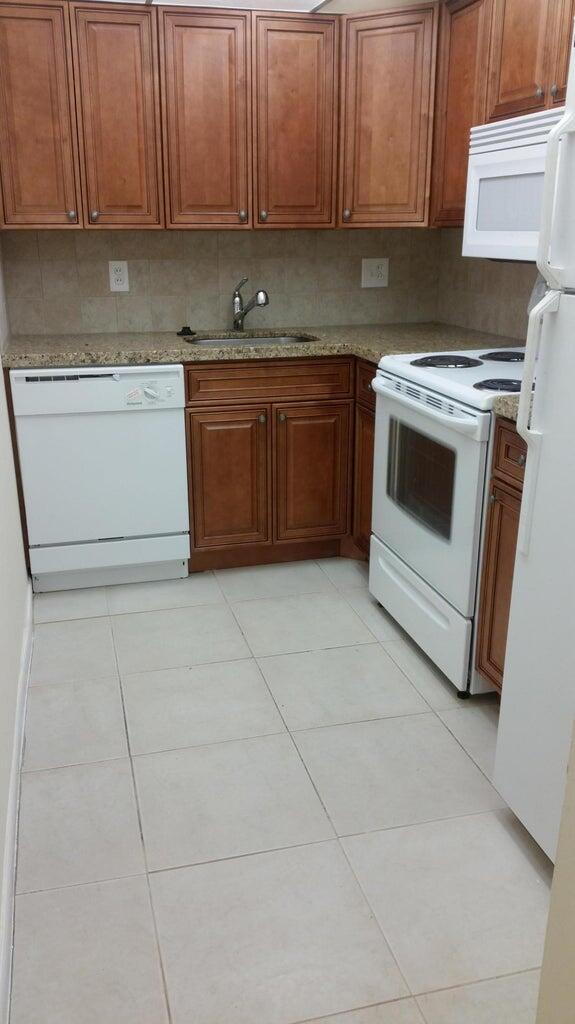 642 Northwest 13th Street, Unit 24 Boca Raton, FL 33486 - Photo 4 of 9 a kitchen with a stove top oven sink and cabinets