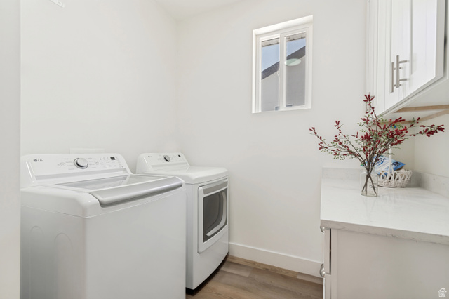683 Kings Landing Tooele, UT 84074 - Photo 15 of 39 Laundry area featuring a window, wood-finish flooring, white cabinetry, a light-toned countertop, and modern appliances