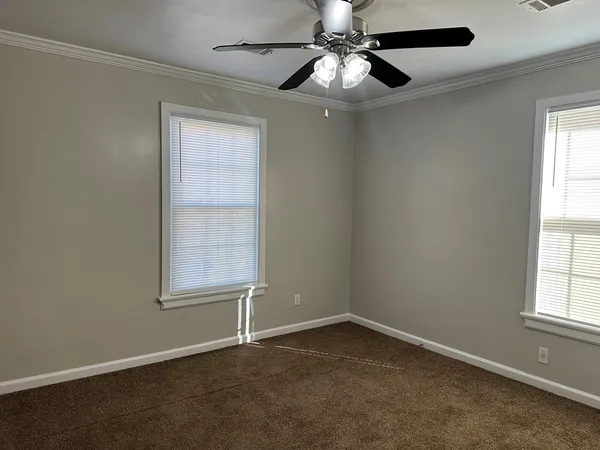 an empty room with windows and fan