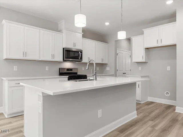 a kitchen with granite countertop a sink a stove oven a counter space and cabinets