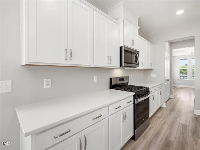 a view of an empty room with wooden floor and windows
