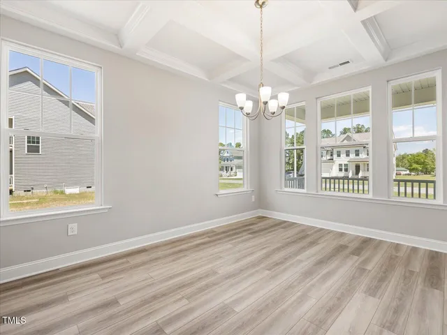 an empty room with wooden floor chandelier and entryway