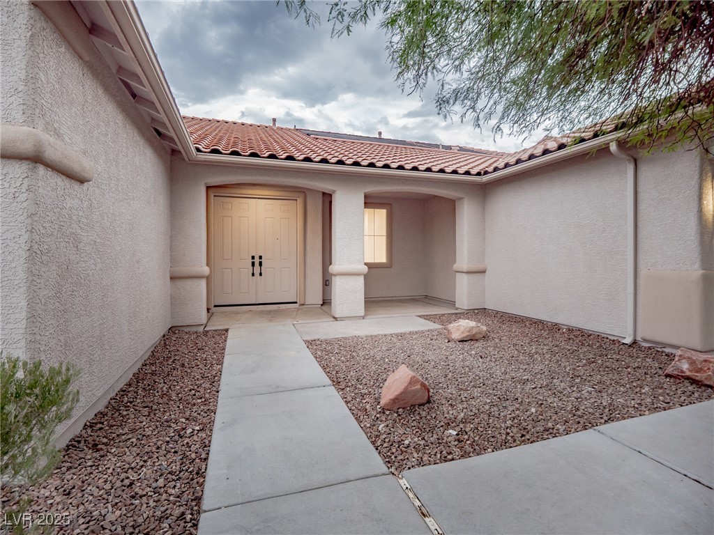 7870 Midnight Ride Street Las Vegas, NV 89131 - Photo 11 of 69 View of exterior entry featuring stucco siding and a tiled roof